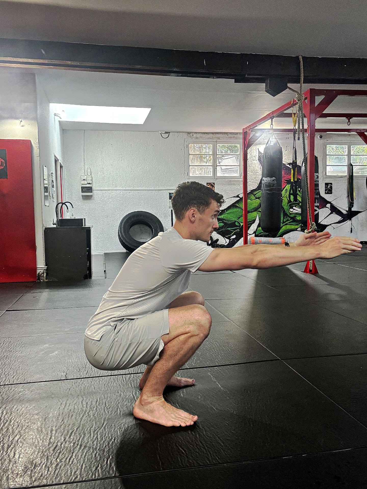 Démonstration du test de squat profond : talons au sol, bras tendus devant